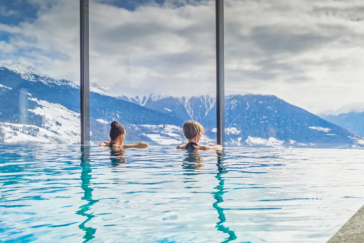 picture of two girls relaxing in a spa in austria in an infinity pool overlooking the mountains