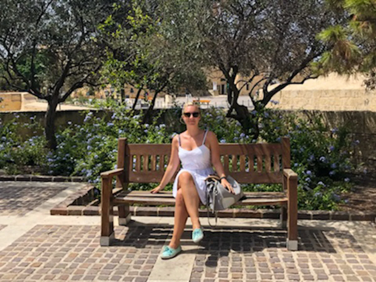 the author sitting on a bench in the upper barrakka gardens in malta