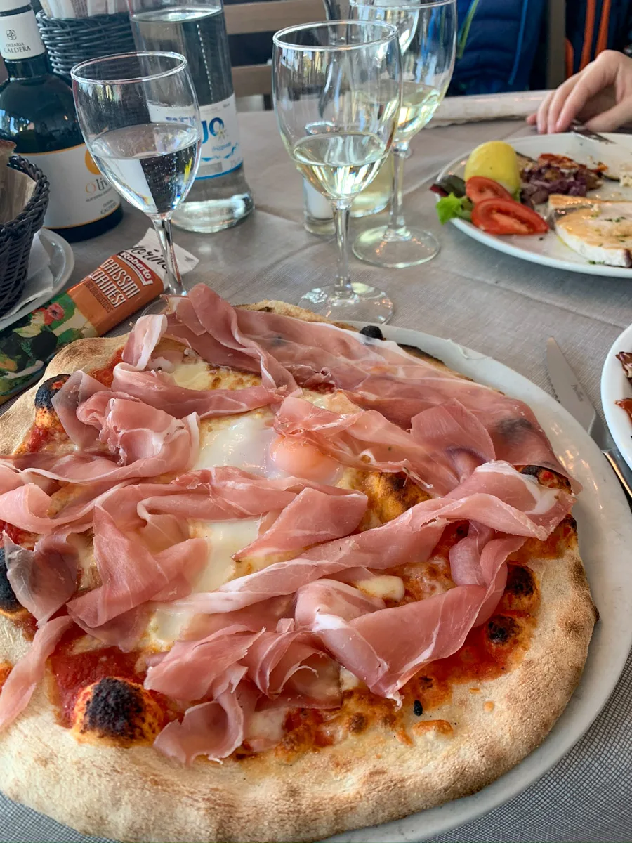 typical italian pizza with egg and prosciutto on it