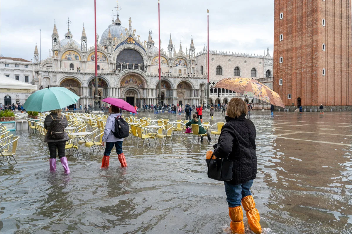 people standin in front of doges palace in high water with umbrellas