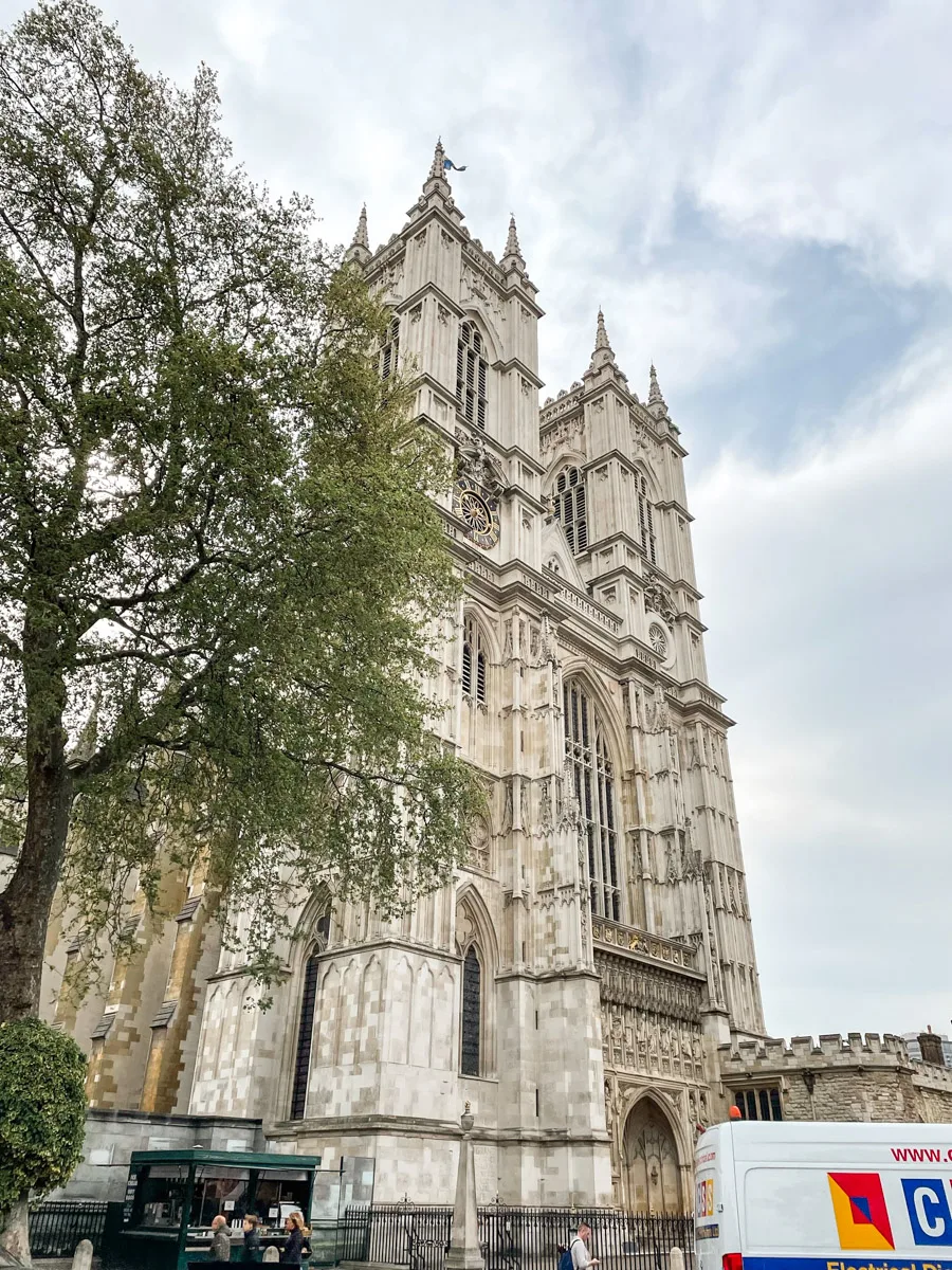 shot of the westminster abbey in london with some trees in front of it in spring