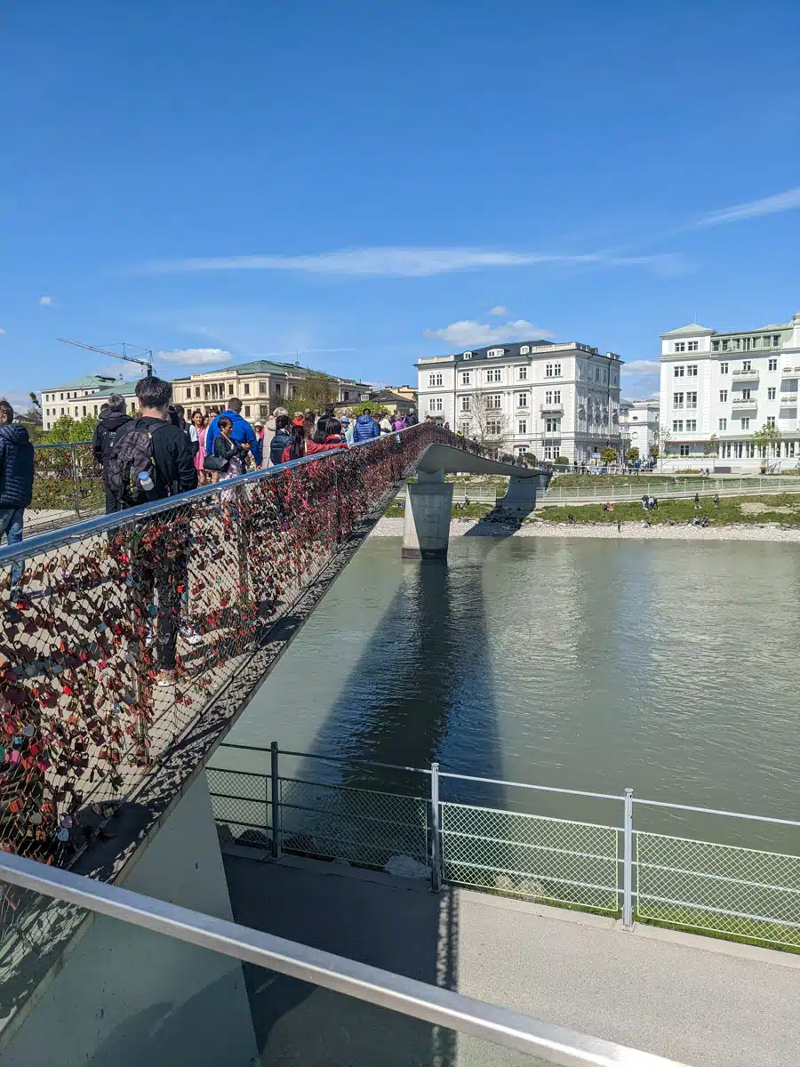 view of old town salzburg and hohensalzburg fortress over the salzach river with pedestrian bridge and love locks