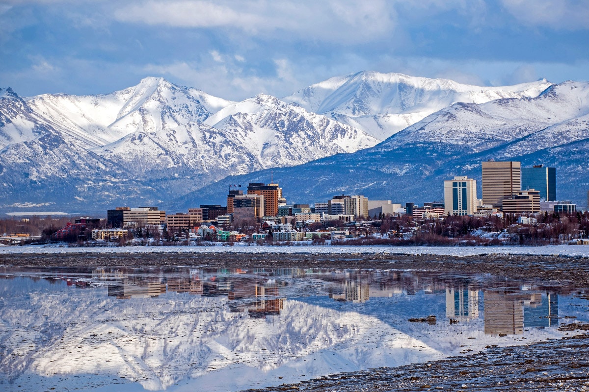 little city of anchorage in alaska in front of beautiful mountain range covered in snow
