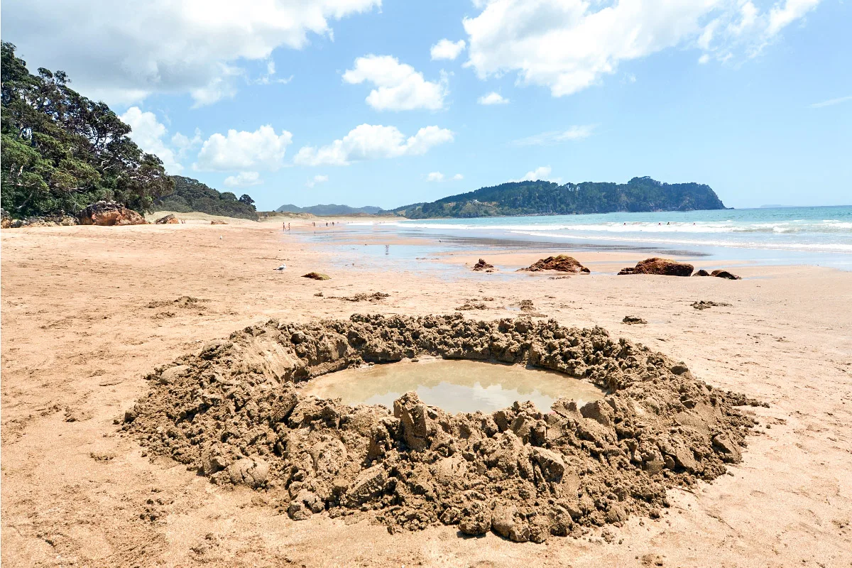 small hole on a beach filled with water from hot springs in new zealand