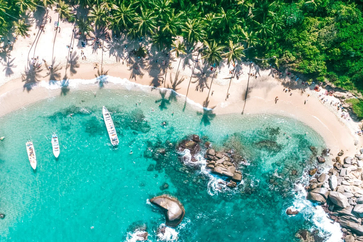 stunning drone shot of tayrona national park with boats floating the crystal clear blue water