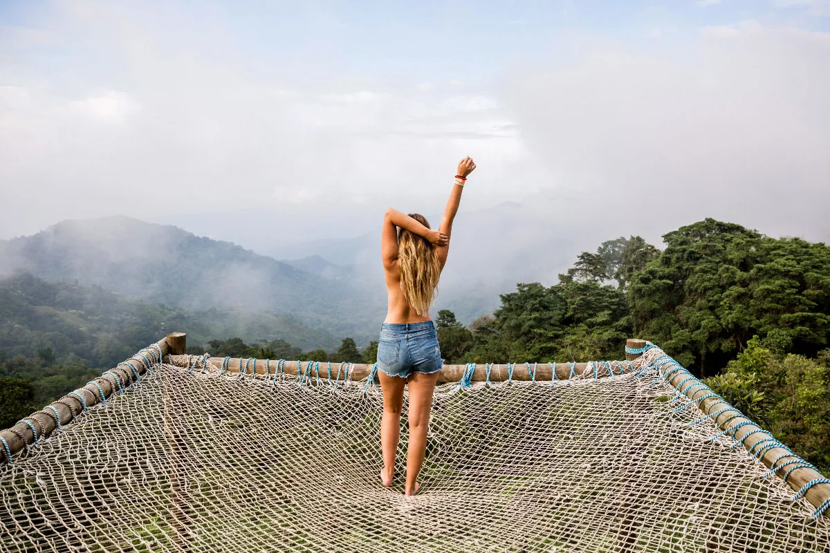 a picture of a girl standing in minca on a terrace posing in front of beautiful mountains