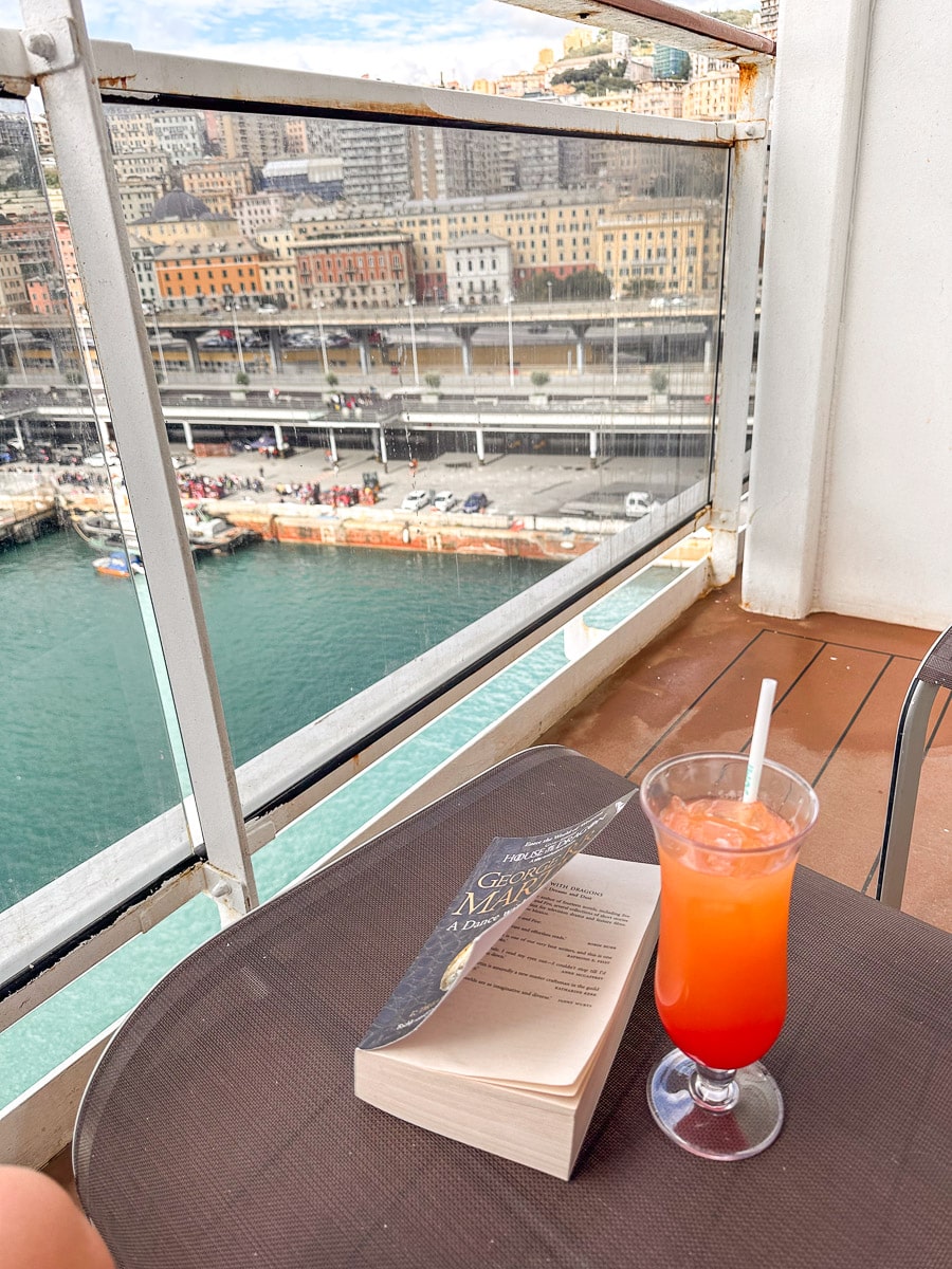 balcony cabin on the msc divina with a book and a cocktail