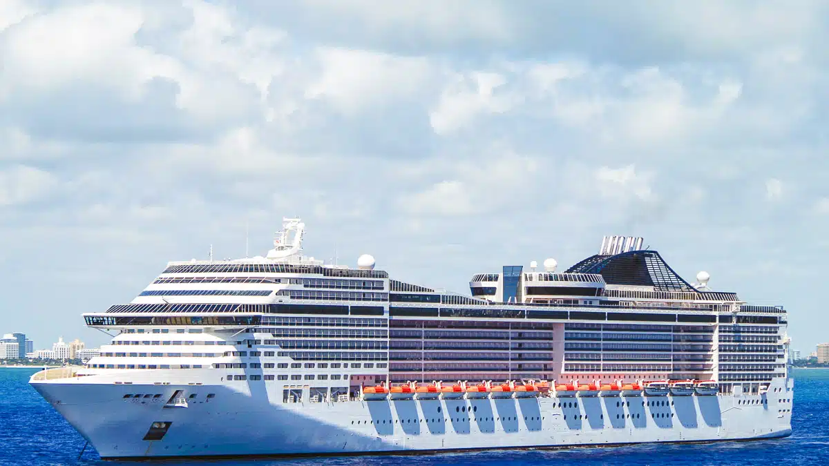 picture of the impressive msc divina floating in the ocean in front of a harbor, impressive cruise ship with 18 decks, picture taken from the side