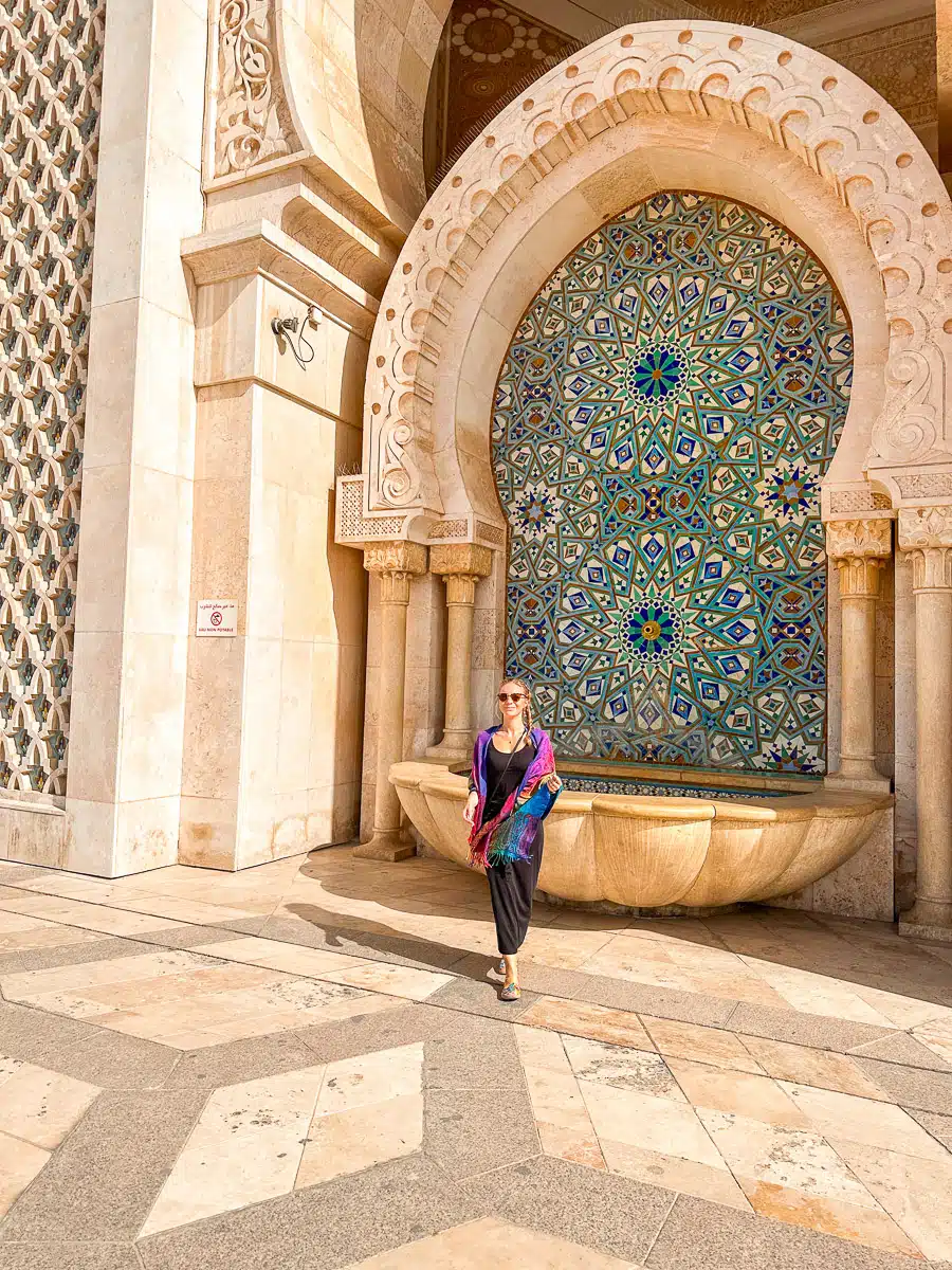 the author in colorful robes in front of a stunning mosque with colorful tiles
