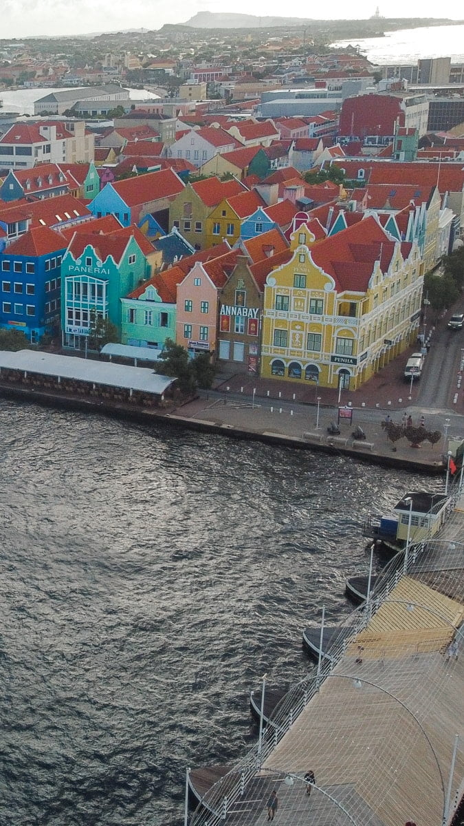 An aerial view captures the vibrant architecture of Curaçao's capital, Willemstad, with its iconic pastel-colored Dutch colonial buildings along the waterfront, a must-visit for history and culture enthusiasts
