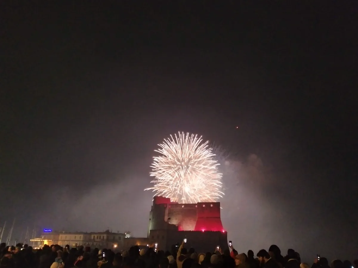 A spectacular New Year's Eve fireworks display at Castel dell'Ovo in Naples, illuminating the night sky above the ancient fortress with bursts of light