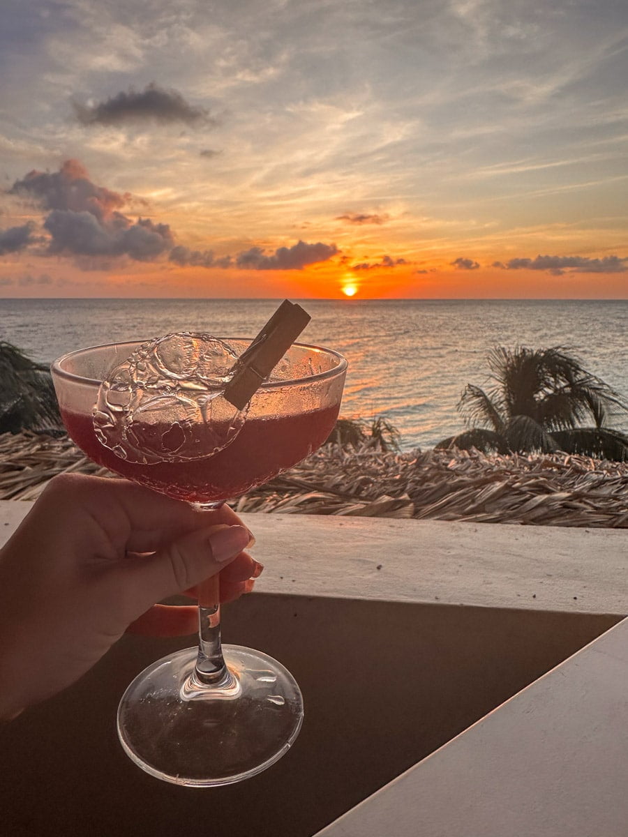 delicious pink cocktail at koraal rooftop restaurant in curacao held over the ocean and the sunset in the background