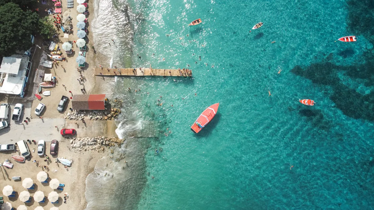 A bird's-eye view of Curaçao's bustling beach scene with boats, swimmers, and sunbathers enjoying the clear blue waters and vibrant beach life. this picture was taken at playa grandi, where fisherman feed the sea turtles 