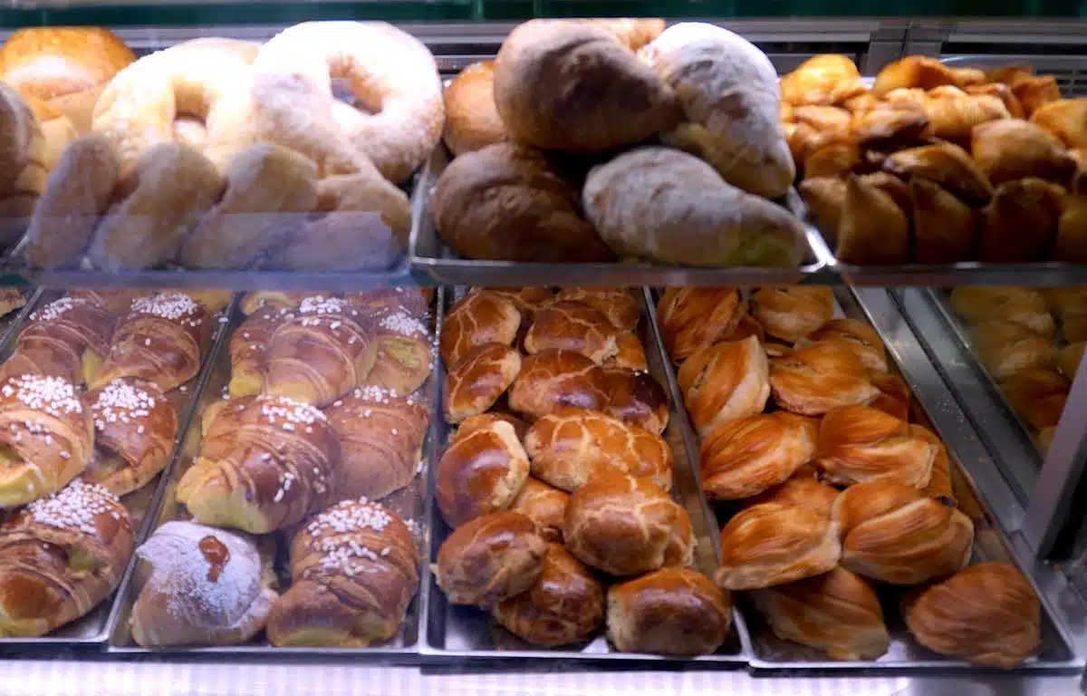 "A tempting display of traditional Neapolitan pastries, including the famous sfogliatella, in a bakery case, showcasing the variety and richness of local sweet treats."