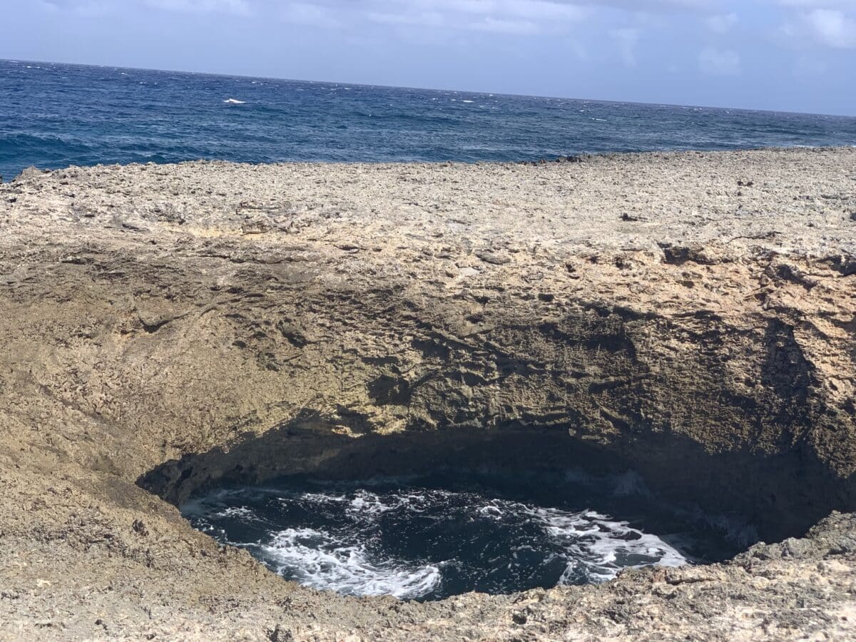 stunning picture of the famous watamaula hole in curacao on the cliffs, one of the coolest spots to visit