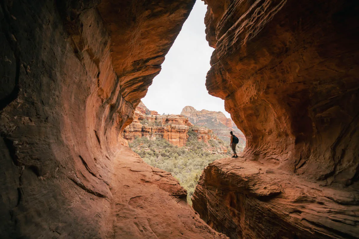 stunning sedona picture of rocks on both sides and a person peeking out onto thelandscape