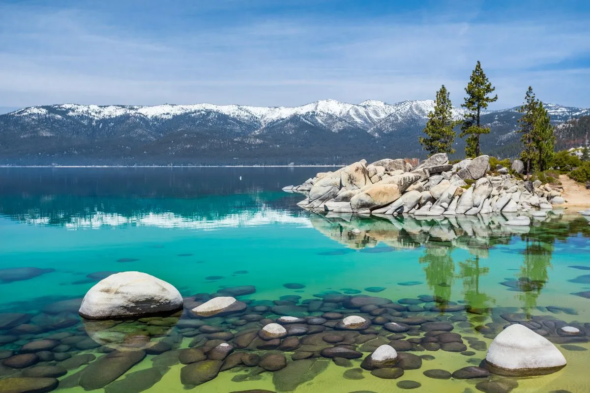 beautiful blue water in lake tahoe with snowy mountains in the background
