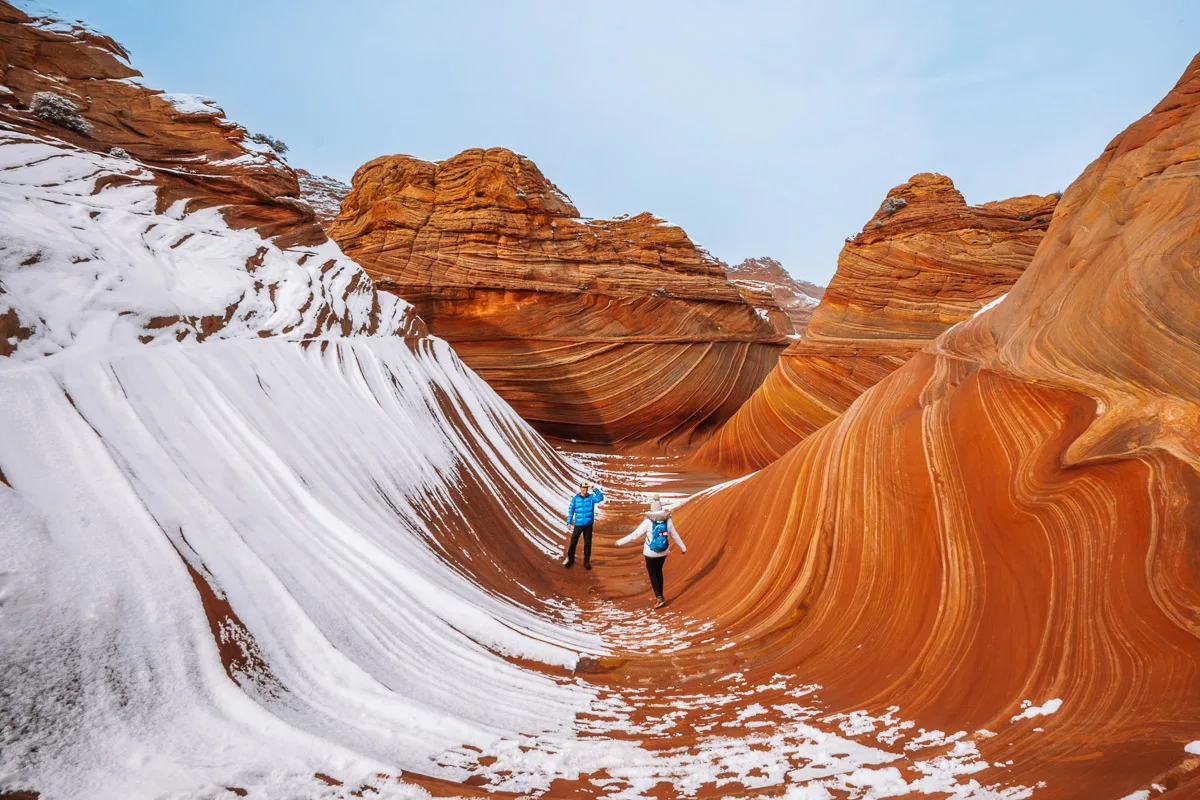 two people hiking the wave in arizona which is covered in snow on one side