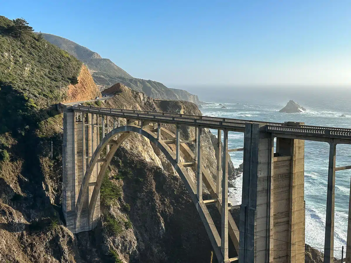 amazing shot of a highway on a bridge between two cliffs with lots of water behind