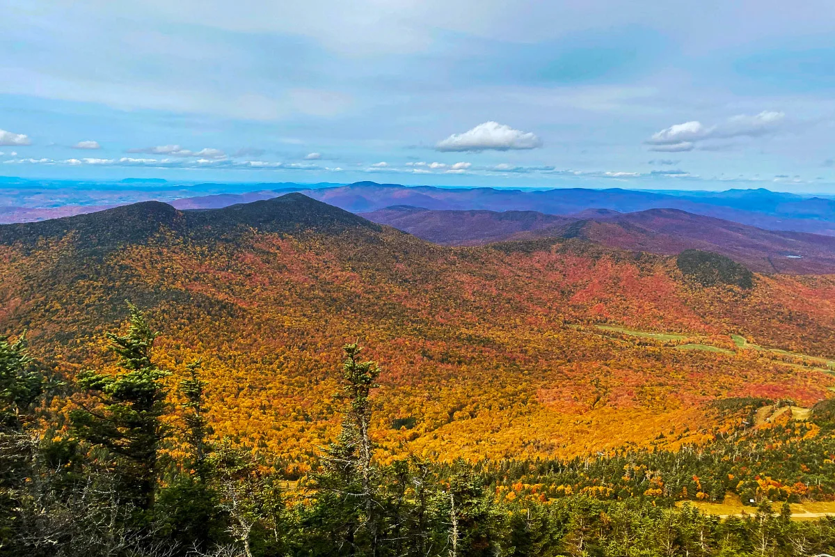 amazing shot from a mountain high up over beautiful orange fall foliage in vermont on the green mountains