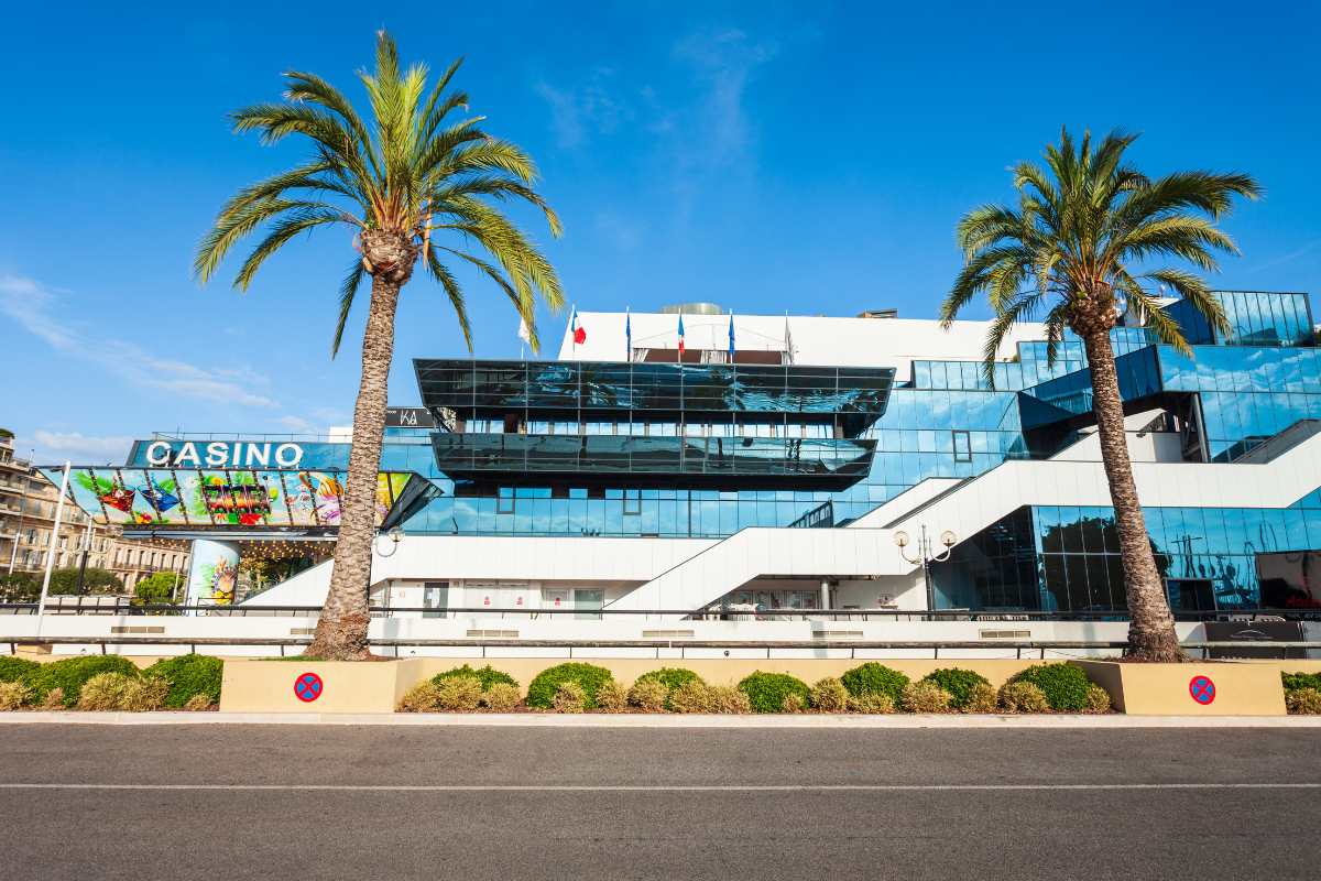 beautiful museum with casino barriere in cannes with some palm trees in front of it, one of the spots that are worth visiting in cannes