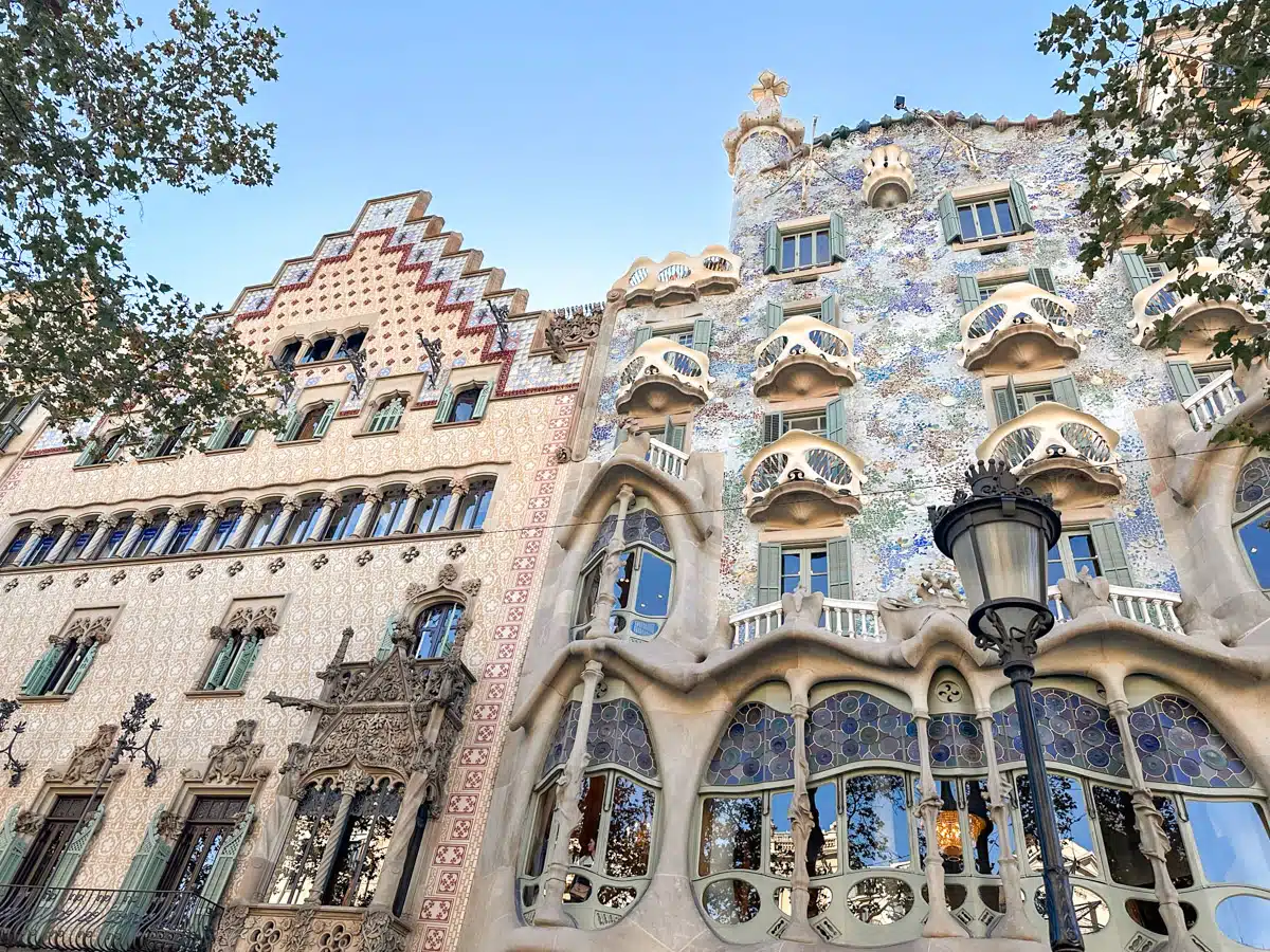 The colorful and whimsical façade of Gaudí's Casa Batlló, with its unique organic shapes and mosaic tiles, under a bright blue sky. One of the things you can't miss on one day in barcelona from cruise ship