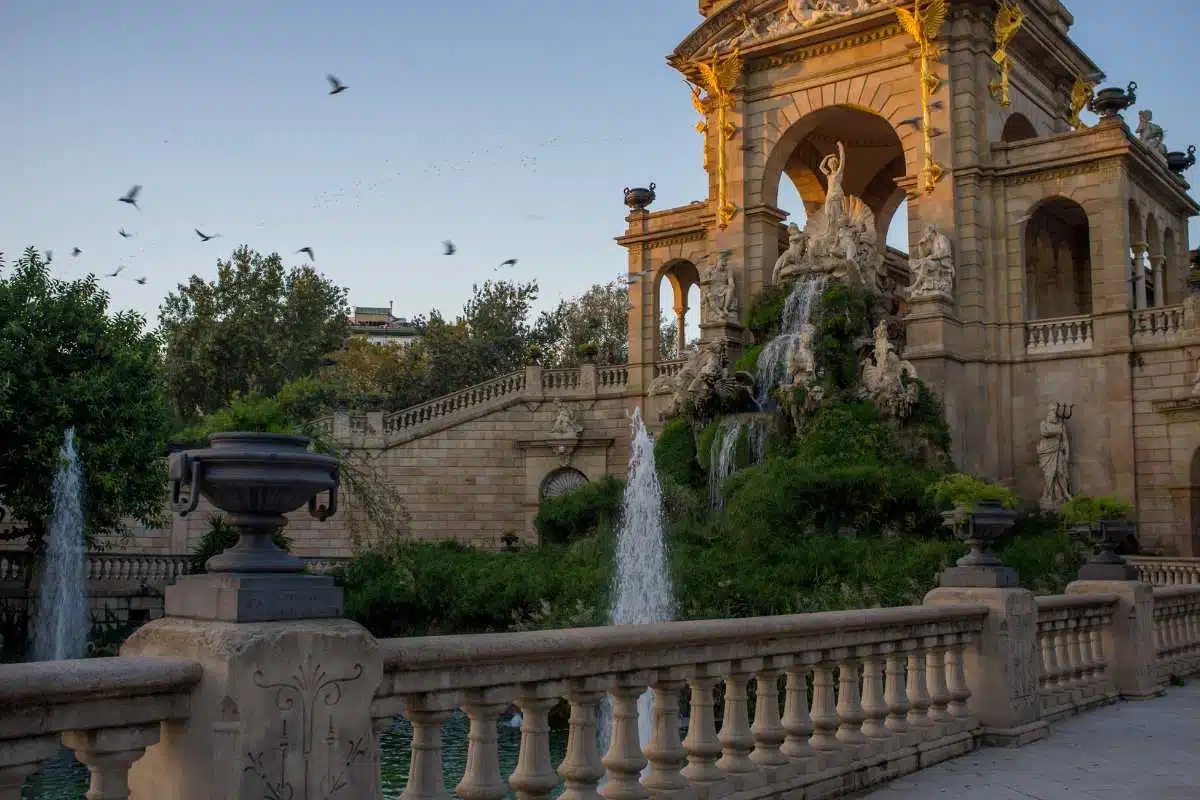 Beautiful picture of the parc de cuitadella, more precicely the cascada fountain at sunset with lots of birds in the air. 