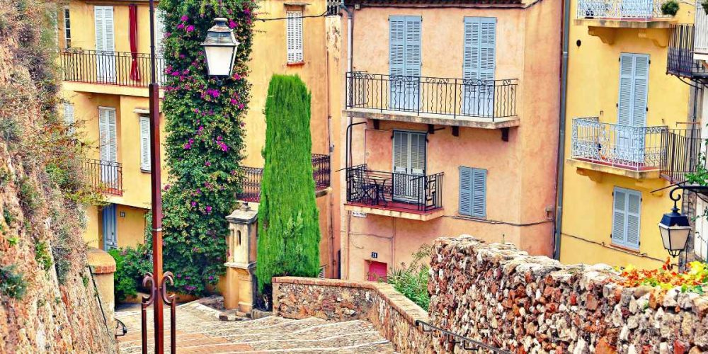 beautiful cobblestone street in cannes with some pastel colored houses in the background