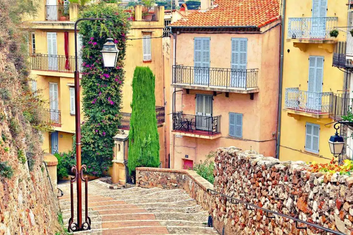 beautiful cobblestone street in cannes with some pastel colored houses in the background