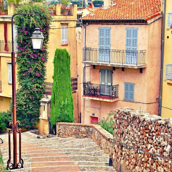 beautiful cobblestone street in cannes with some pastel colored houses in the background