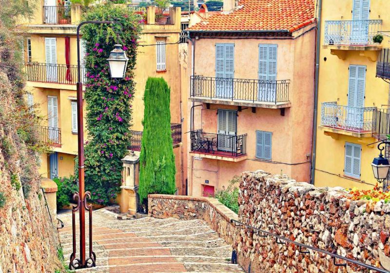 beautiful cobblestone street in cannes with some pastel colored houses in the background
