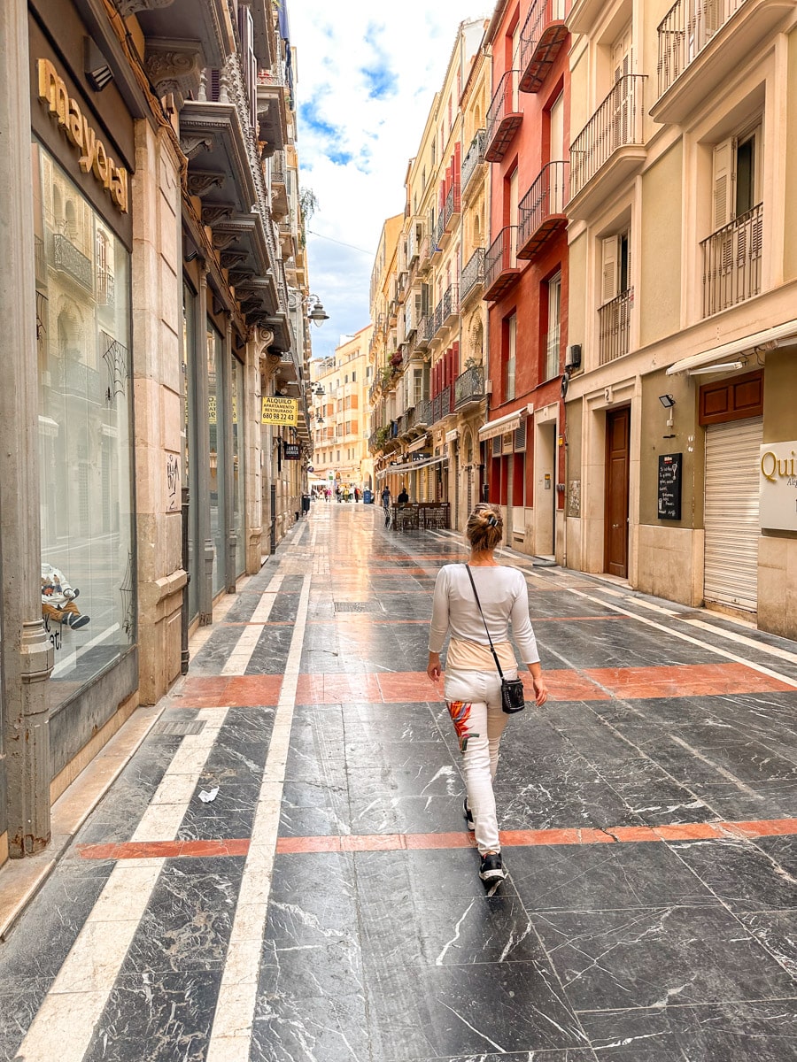 the author walking down a marble-tiled pedestrian street in Málaga’s historic center, with colorful buildings on either side.