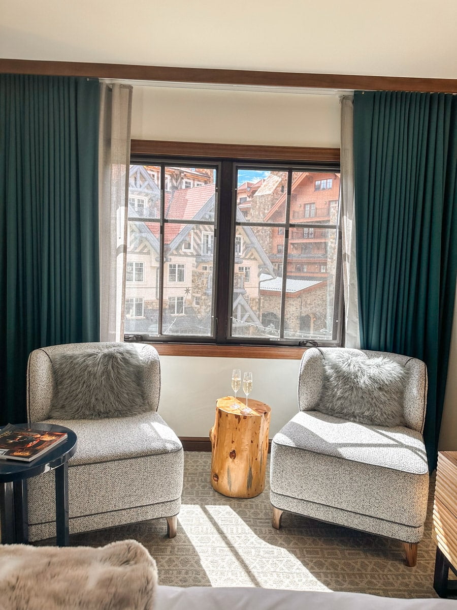 A cozy hotel room with two chairs and some champagne.