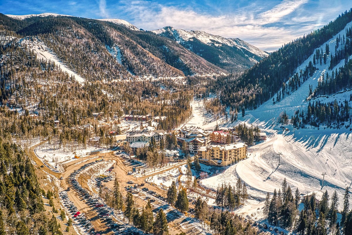 drone shot of the valley and ski resorts with lots of cars and hotels in taos nm