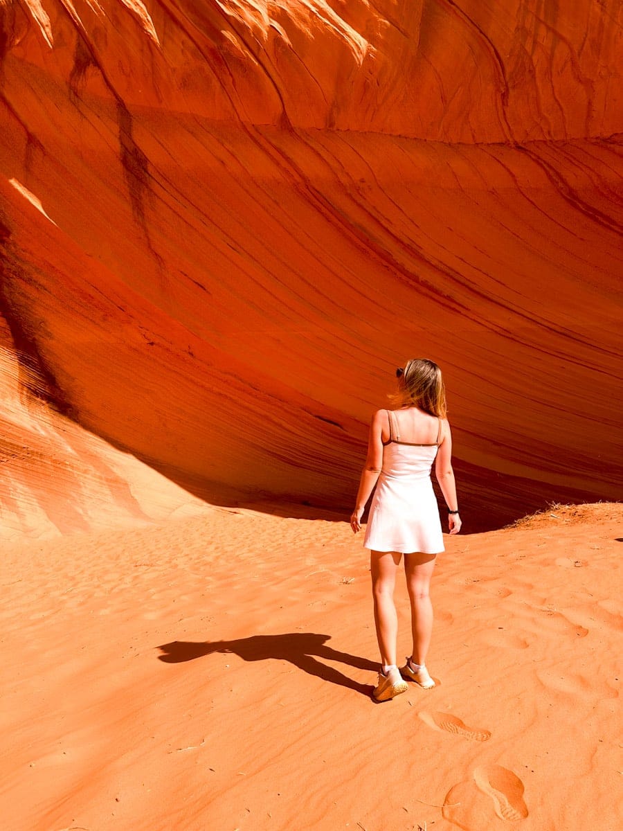 the authors wife in a white dress standing against the striking orange sandstone curves of a canyon, enjoying the warm glow of the rock formations in Page, Arizona.