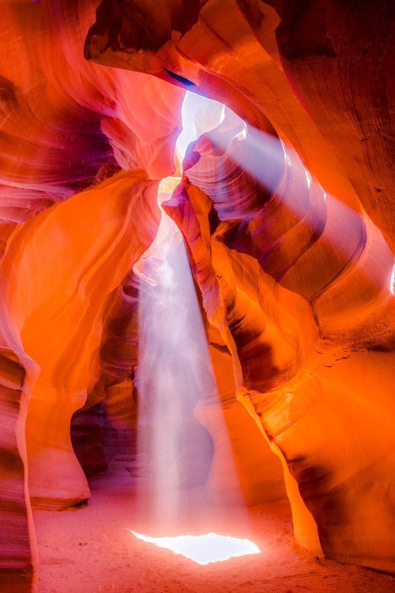 Antelope Canyon in the Navajo Reservation near Page, Arizona, USA. The smooth, flowing sandstone curves inside a slot canyon, illuminated with vibrant shades of orange and red, under a blue sky