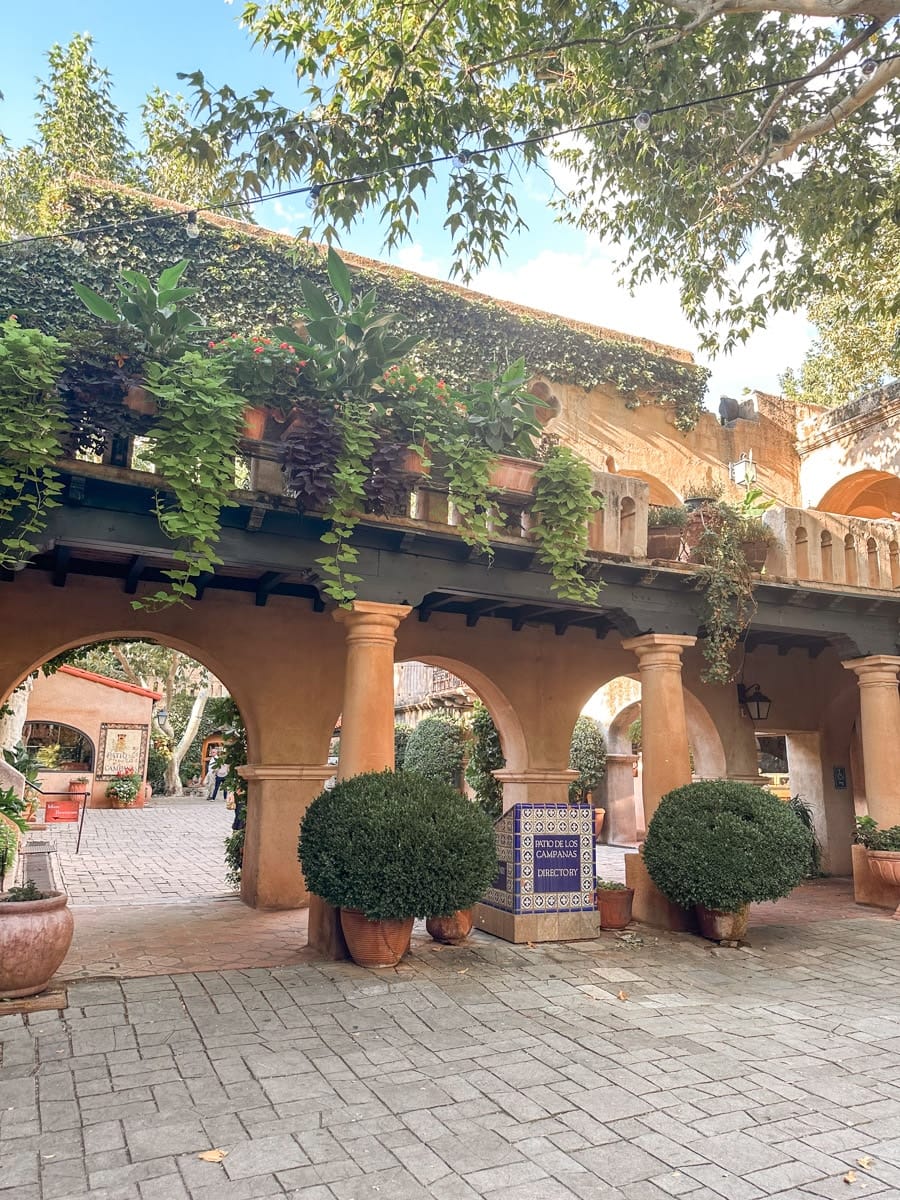 A small stone fountain surrounded by plants in front of a charming building with an art gallery sign in Sedona, Arizona.