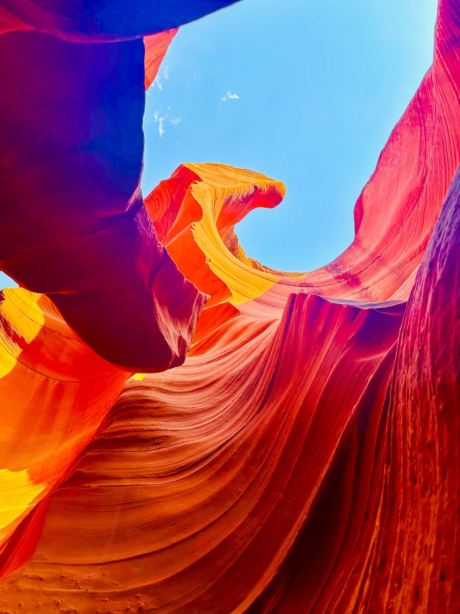 A stunning shot of a slot canyon in Sedona with vibrant red and orange sandstone formations against a bright blue sky.