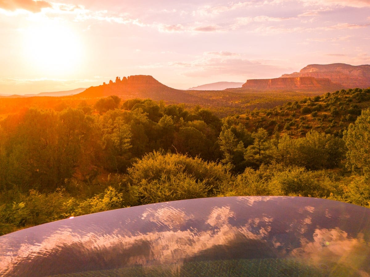 A beautiful aerial shot of Sedona’s red rock buttes and desert landscape, illuminated by the soft glow of sunset.