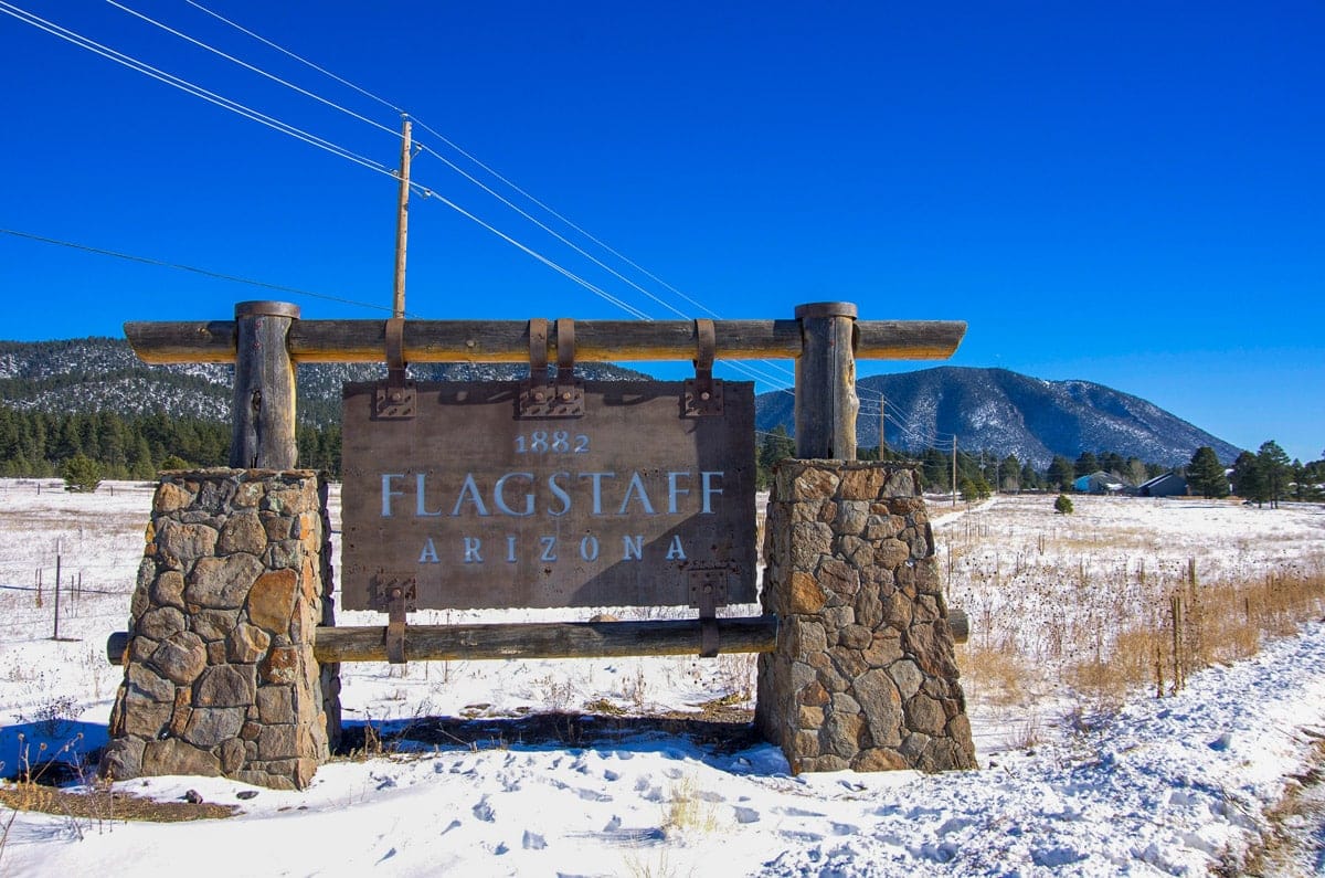 the sign of flagstaff arizona with some snow on the ground