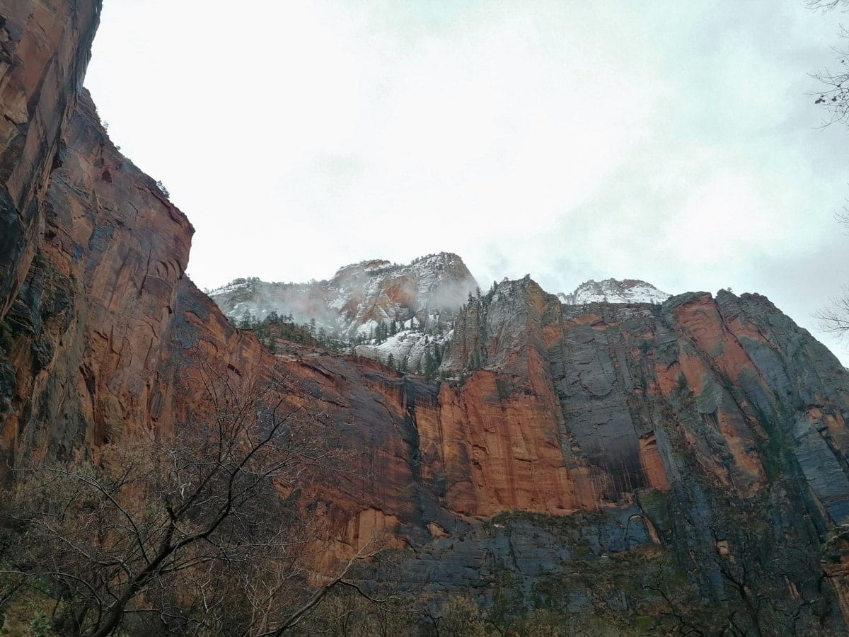 Snow-dusted red rock cliffs at Zion National Park under a cloudy winter sky.