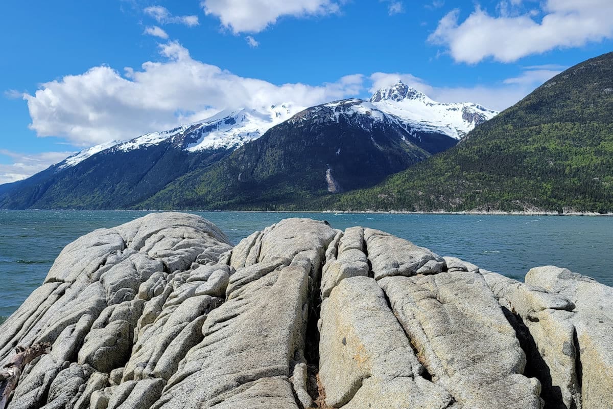 A vibrant icy scene of a bright blue glacial meltwater river winding through smooth, white ice formations in Alaska.