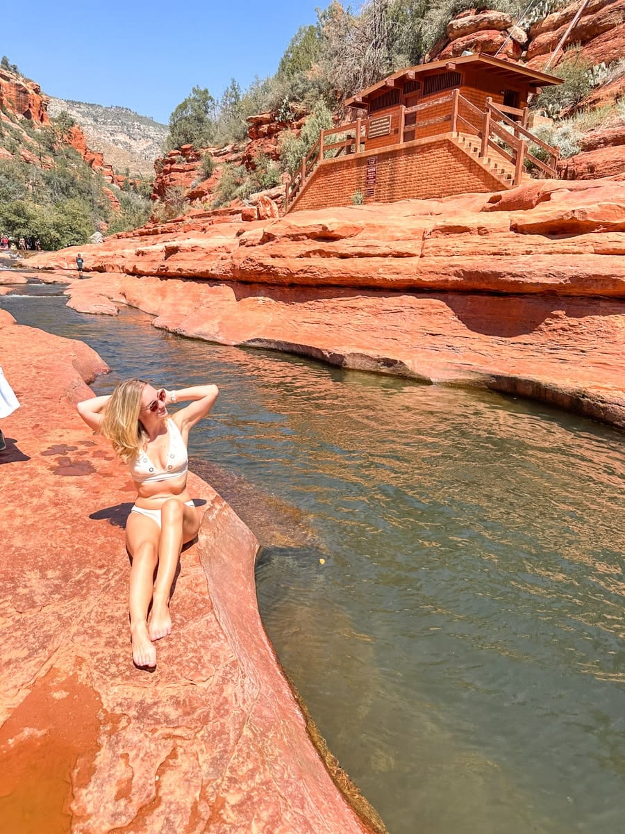 the author's wife sitting next to a creek at slide rock state park