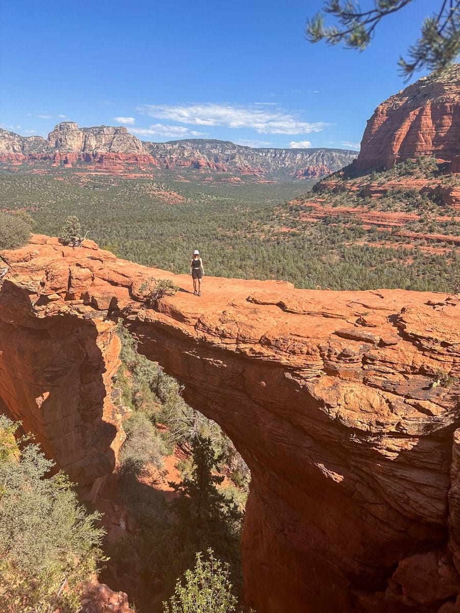 the author's wife posing on a natural bridge in sedona