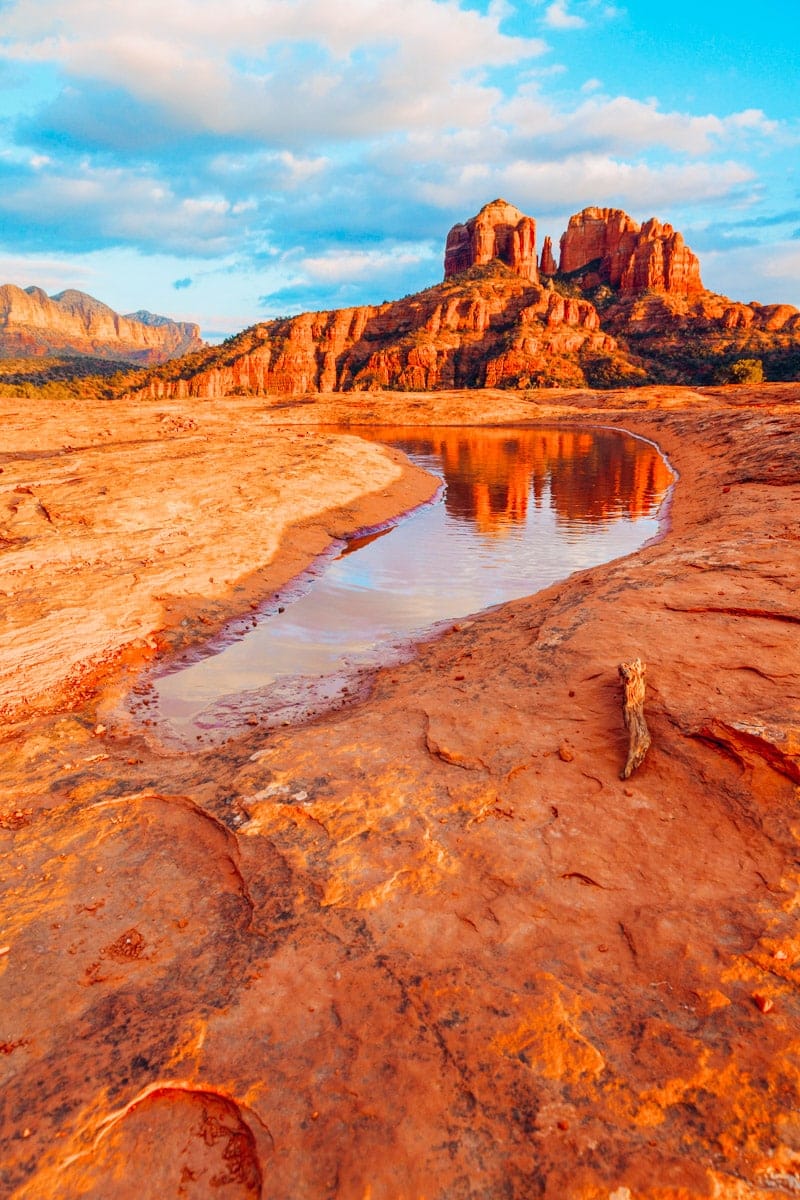 Cathedral Rock in the distance is reflected in a pool of water at sunset