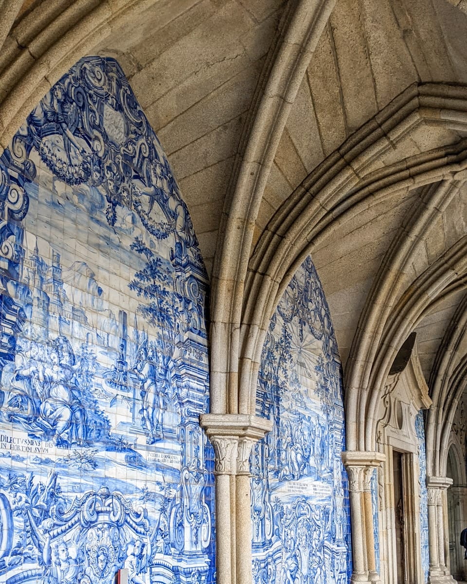 Azulejo tiles in Porto’s cathedral cloister – A close-up of the intricate blue and white ceramic tile murals adorning the Gothic stone arches of a historic church in Porto.