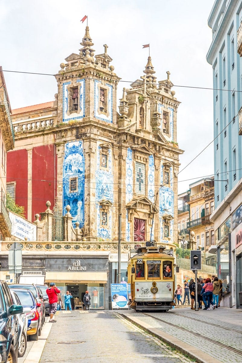Historic São Bento Church and vintage tram – A picturesque street in Porto featuring the ornate blue-tiled façade of a historic church, with a classic yellow tram passing by.