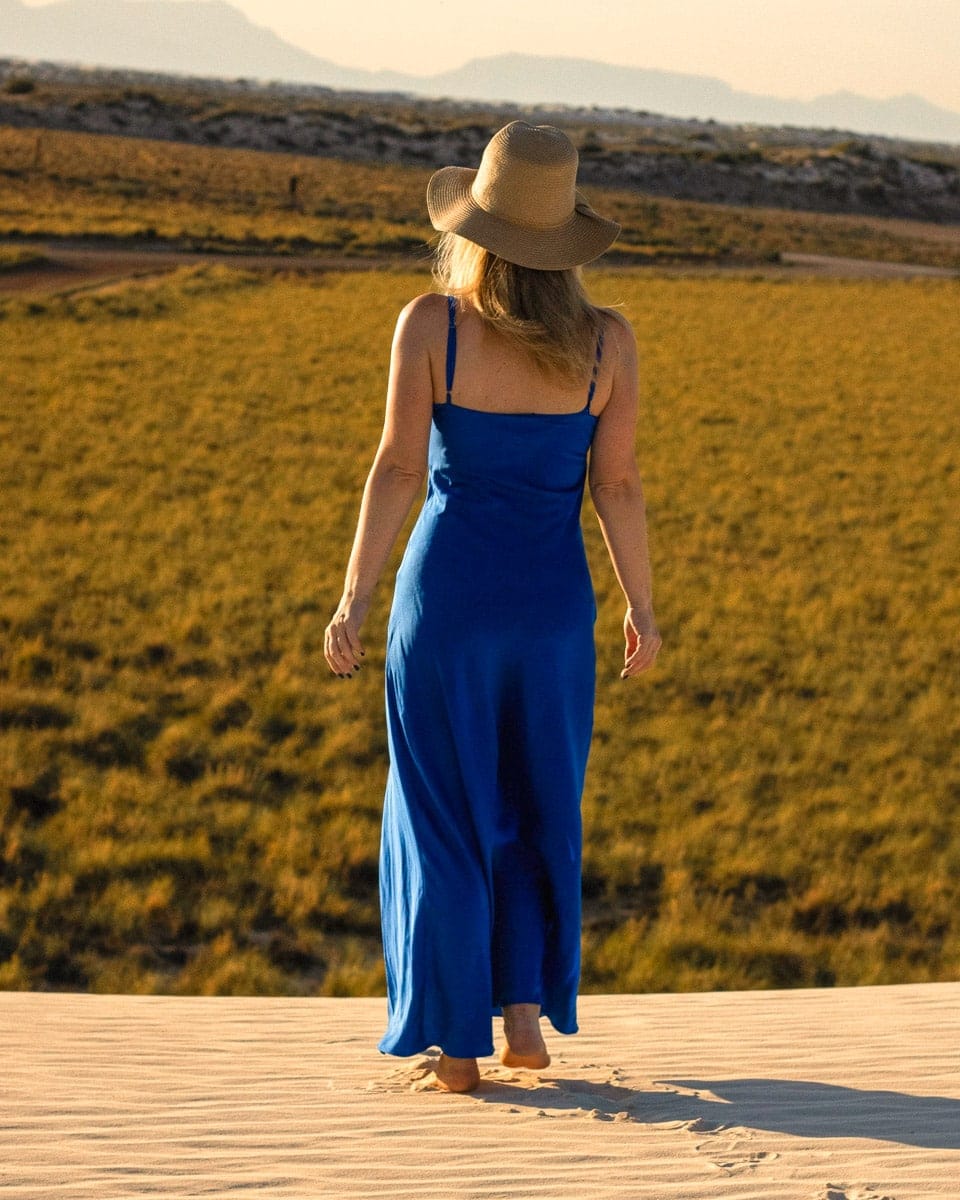 the authors wife overlooking the sandy parts of white sands from a sand dune in a blue dress and a sunhat