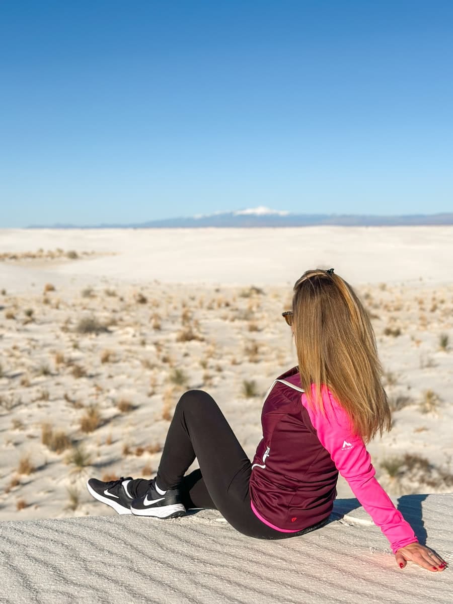 the author's wife chilling on a white sand dune in a hiker's outfit at the backcountry camping trail