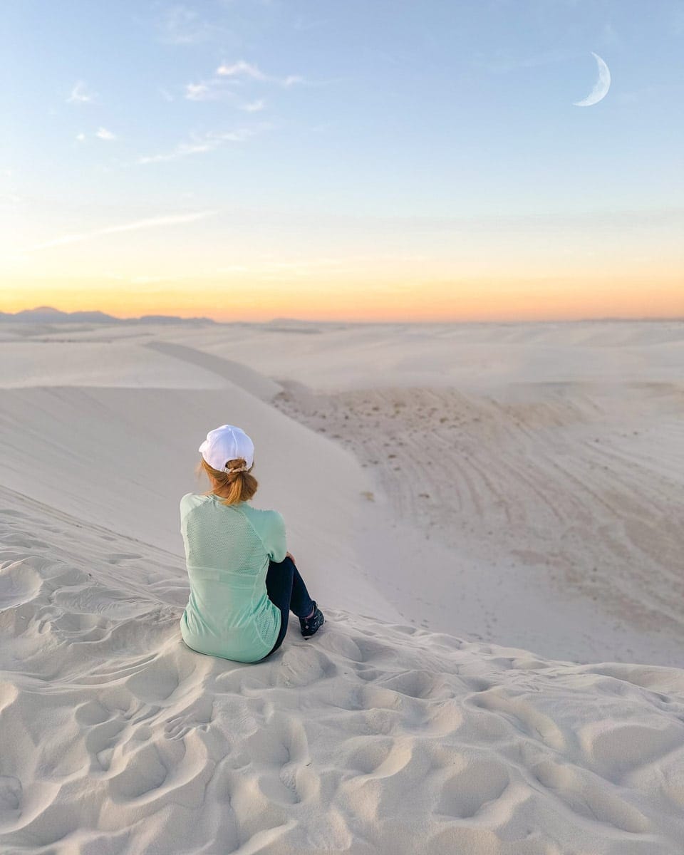 the author's wife sitting in the white sand dunes in new mexico at the alkali flat trail